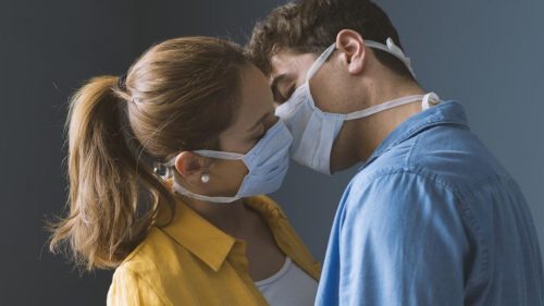 2 adults in masks kissing