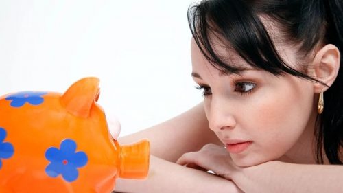 girl looking at a piggy bank