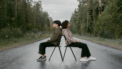 a man and woman sitting on chair with their back touching