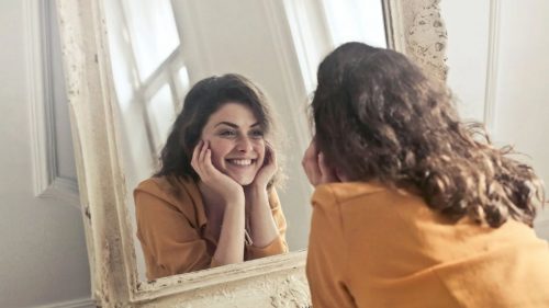 a happy woman looking in a mirror