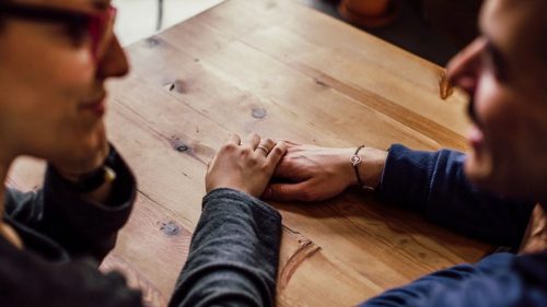 a girl and guy touching hands on table