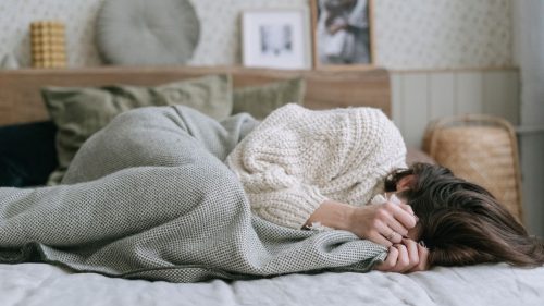 woman lying on couch with face covered