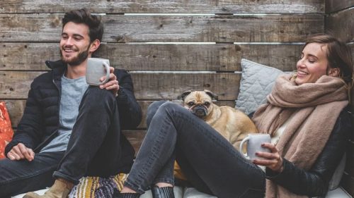 happy couple enjoying coffee with their dog