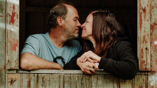 couple romantically touching nose on a window